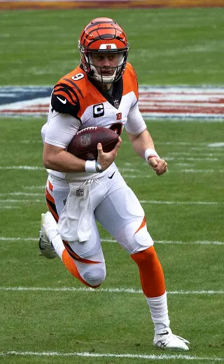 Joe Burrow wearing jersey number 9 running on the field during a game, displaying leadership and agility as he leads the Cincinnati Bengals offense.