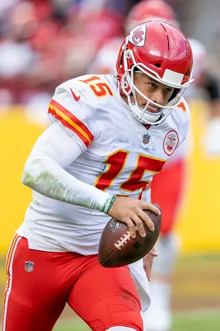 Patrick Mahomes in action during an NFL game, showcasing his exceptional skills as he throws a touchdown pass, with a packed stadium of cheering fans in the background, under bright lights.