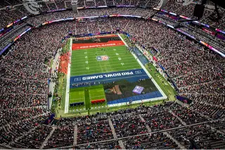 An NFL stadium filled with enthusiastic fans under bright lights, creating an electrifying atmosphere as they cheer for their teams. The energy is palpable, showcasing the passion and excitement of a live football game.